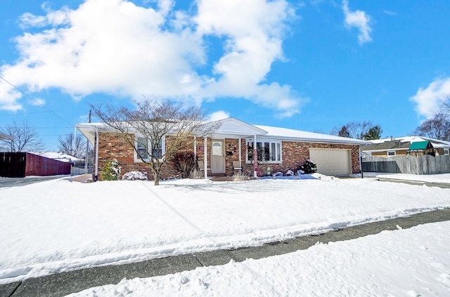 ranch-style home with an attached garage, fence, and brick siding