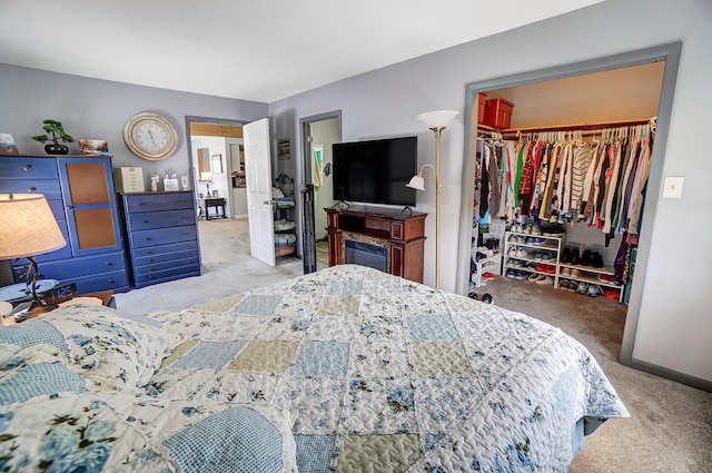 carpeted bedroom with a closet, a spacious closet, and baseboards