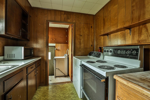 1024 Ansel Dr, Dayton, OH 45419 - kitchen featuring electric stove, stainless steel microwave, light floors, wooden walls, and independent washer and dryer