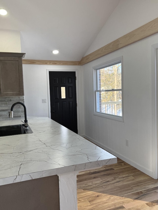 kitchen featuring lofted ceiling, sink, and light wood-type flooring