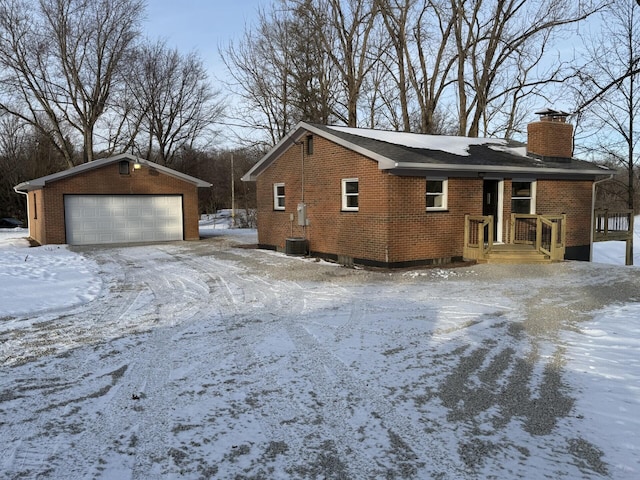 view of snowy exterior featuring a garage and an outdoor structure