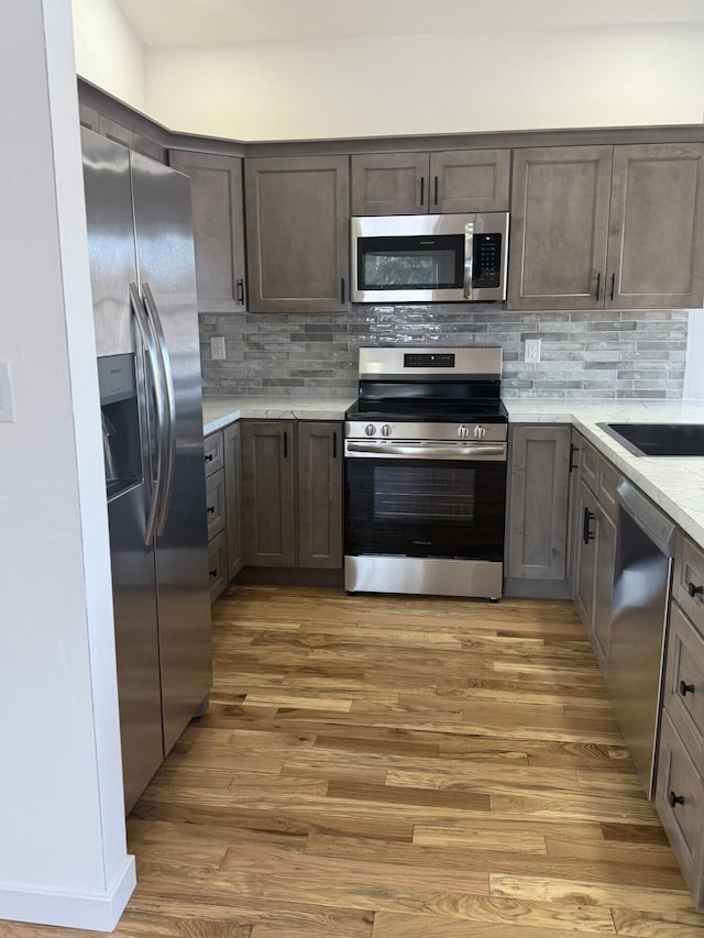 kitchen featuring dark brown cabinetry, backsplash, hardwood / wood-style flooring, and stainless steel appliances