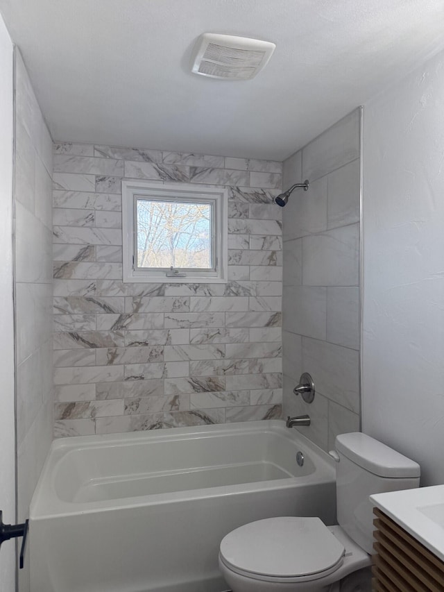 full bathroom featuring tiled shower / bath combo, vanity, and toilet