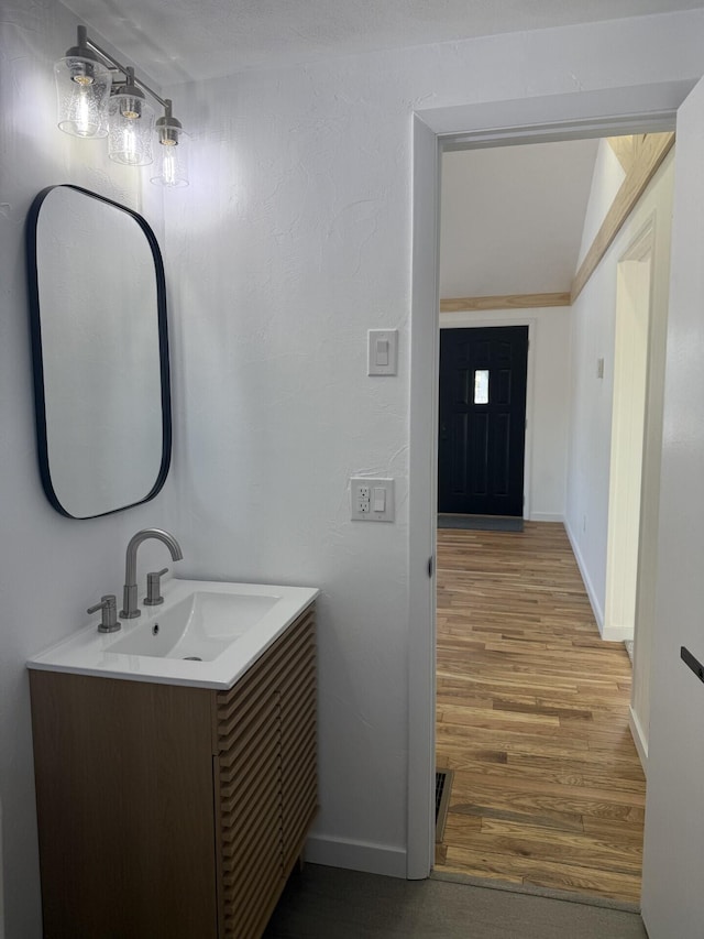 bathroom with vanity, hardwood / wood-style flooring, and lofted ceiling