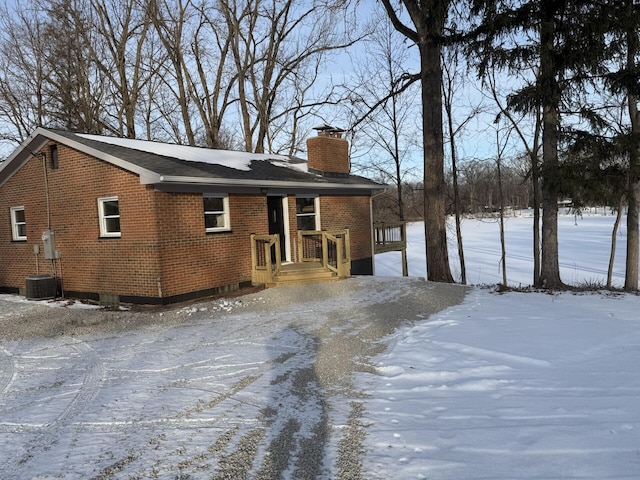 snow covered rear of property featuring central air condition unit