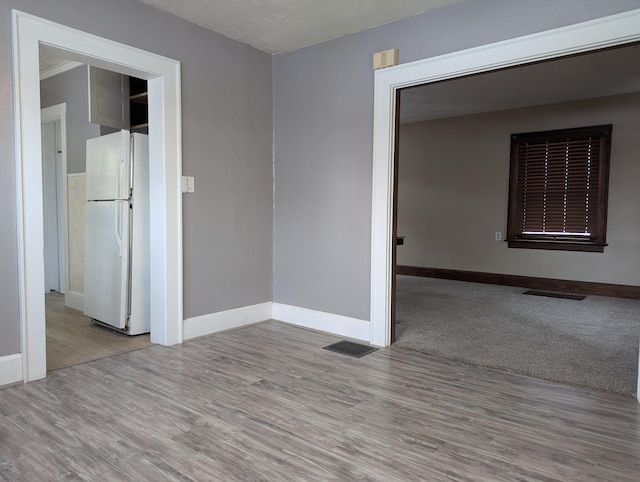 empty room featuring light wood-style flooring, visible vents, and baseboards