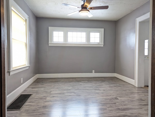 spare room with visible vents, plenty of natural light, light wood finished floors, and ceiling fan