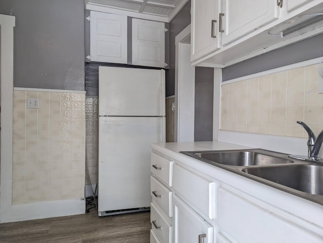 kitchen with dark wood-style flooring, light countertops, freestanding refrigerator, white cabinetry, and a sink