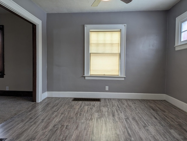 unfurnished room featuring baseboards, visible vents, ceiling fan, and wood finished floors