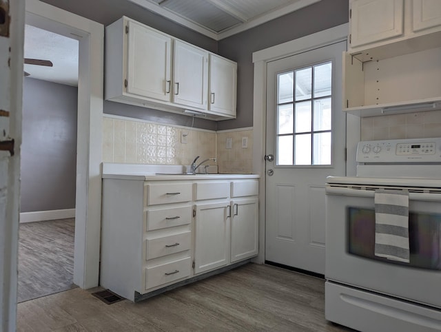 kitchen with a sink, electric stove, light countertops, and white cabinetry