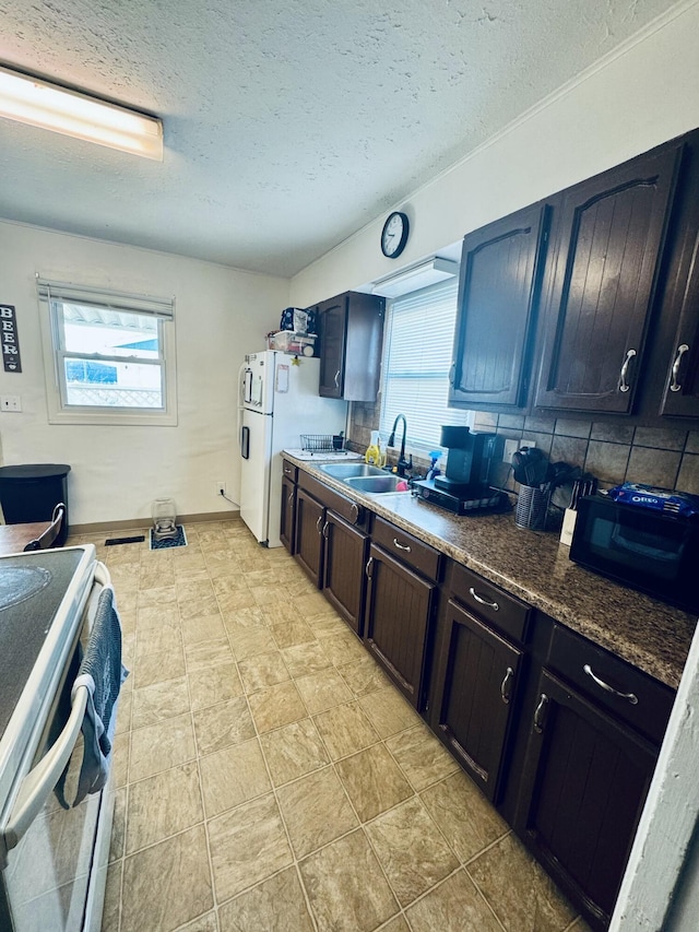 kitchen with tasteful backsplash, dark countertops, a sink, a textured ceiling, and range with electric cooktop