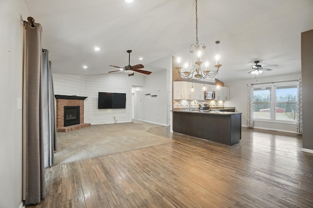 kitchen featuring open floor plan, hanging light fixtures, tasteful backsplash, and a brick fireplace