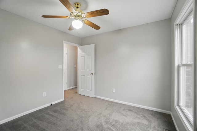 empty room featuring carpet flooring, a ceiling fan, and baseboards