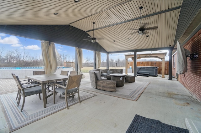 view of patio with a hot tub, ceiling fan, a fenced backyard, an outdoor living space, and outdoor dining space