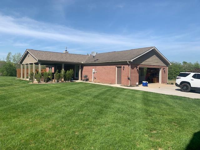 single story home with a front yard, brick siding, driveway, and an attached garage