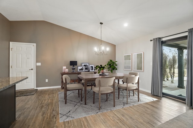 dining room with lofted ceiling, baseboards, wood finished floors, and a chandelier