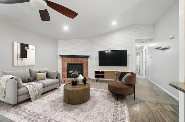 living room featuring visible vents, a ceiling fan, wood finished floors, vaulted ceiling, and a brick fireplace