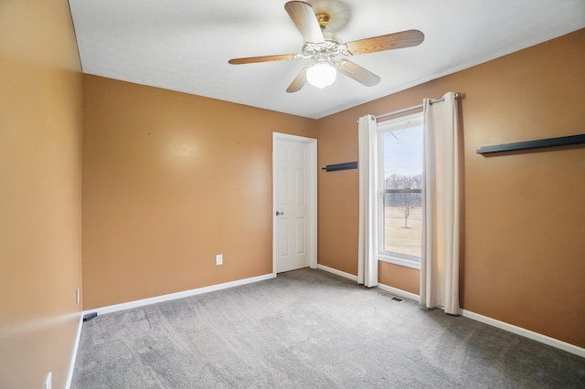 carpeted spare room with ceiling fan, visible vents, and baseboards