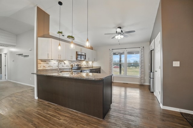 kitchen with a sink, white cabinets, appliances with stainless steel finishes, dark stone countertops, and pendant lighting