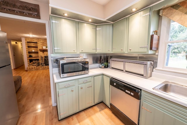 17689 Fort Loramie Swanders Rd, Sidney, OH 45365 - kitchen with white dishwasher, stainless steel microwave, green cabinets, light countertops, and light wood finished floors