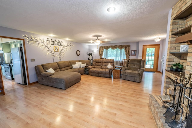 17689 Fort Loramie Swanders Rd, Sidney, OH 45365 - living room with a fireplace, a textured ceiling, light wood-type flooring, and a ceiling fan