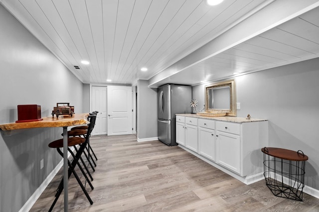 kitchen featuring recessed lighting, white cabinets, freestanding refrigerator, and light wood-style floors