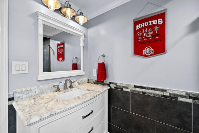 bathroom with tile walls, a wainscoted wall, vanity, and crown molding