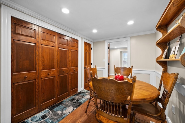 dining area with a wainscoted wall, recessed lighting, dark wood-type flooring, crown molding, and a decorative wall