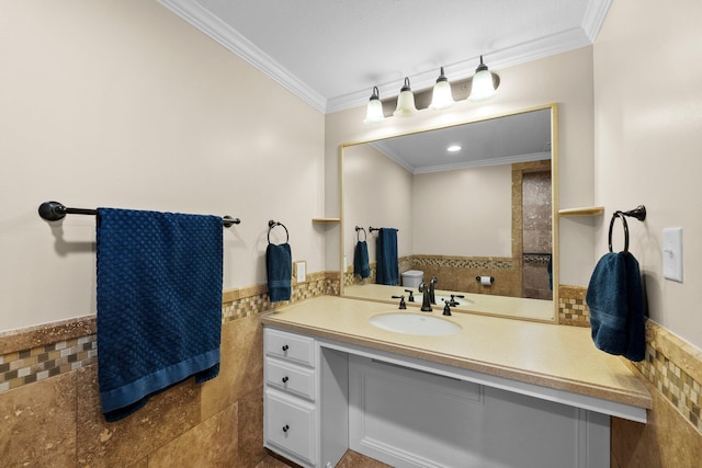 bathroom featuring a wainscoted wall, tile walls, vanity, and ornamental molding