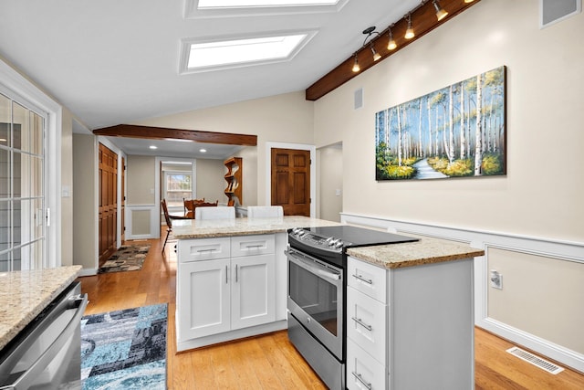 kitchen with visible vents, lofted ceiling with skylight, a kitchen island, stainless steel appliances, and white cabinets