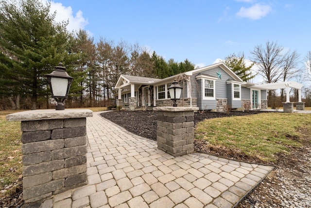 view of front of house featuring stone siding, covered porch, a chimney, and a front yard