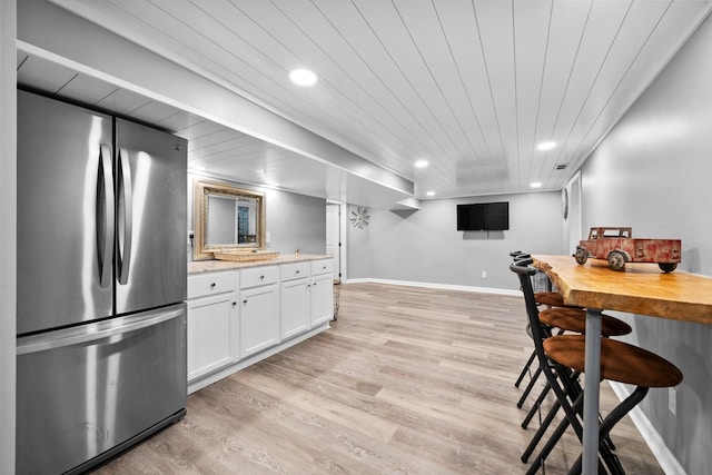 kitchen with light wood finished floors, baseboards, recessed lighting, freestanding refrigerator, and white cabinets