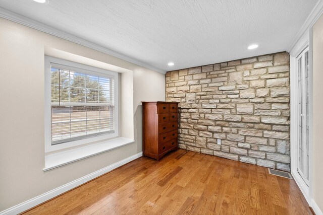 interior space featuring a textured ceiling, wood finished floors, visible vents, and ornamental molding