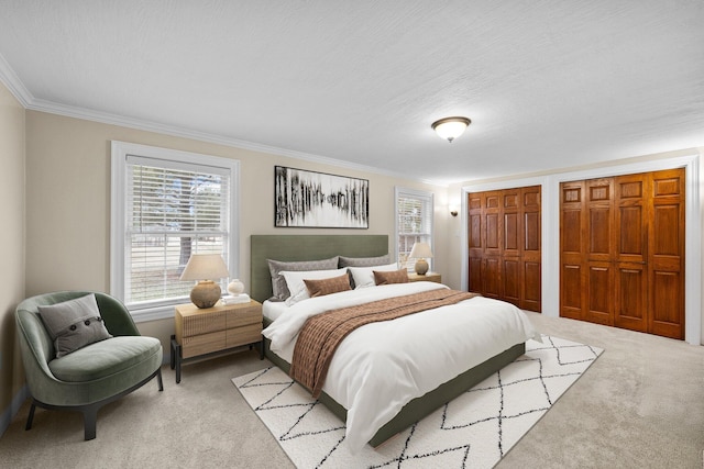 bedroom featuring light carpet, a textured ceiling, ornamental molding, and multiple closets