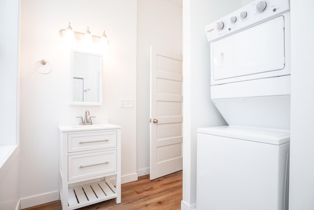 washroom featuring sink, light hardwood / wood-style floors, and stacked washing maching and dryer