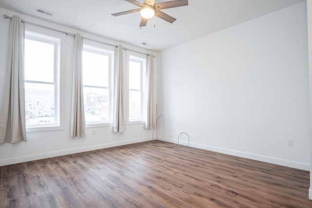 unfurnished room featuring ceiling fan, a healthy amount of sunlight, and dark hardwood / wood-style flooring