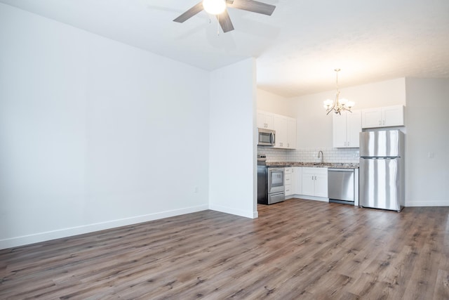 kitchen featuring dark wood-type flooring, white cabinetry, hanging light fixtures, stainless steel appliances, and decorative backsplash