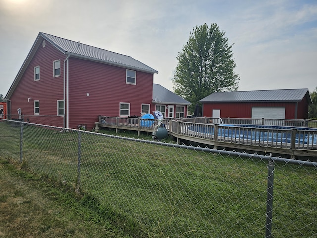 6822 Watercraft Dr, Huntsville, OH 43324 - back of house featuring a fenced backyard, a detached garage, a metal roof, an outdoor structure, and a deck