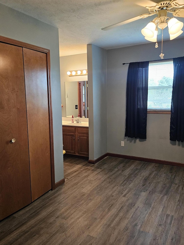 6822 Watercraft Dr, Huntsville, OH 43324 - unfurnished bedroom featuring dark wood finished floors, ceiling fan, a closet, ensuite bathroom, and a textured ceiling