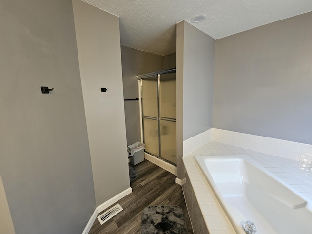 2973 Kicking Bird Trce, Dublin, OH 43017 - full bathroom with wood finished floors, a shower stall, a garden tub, and a textured ceiling