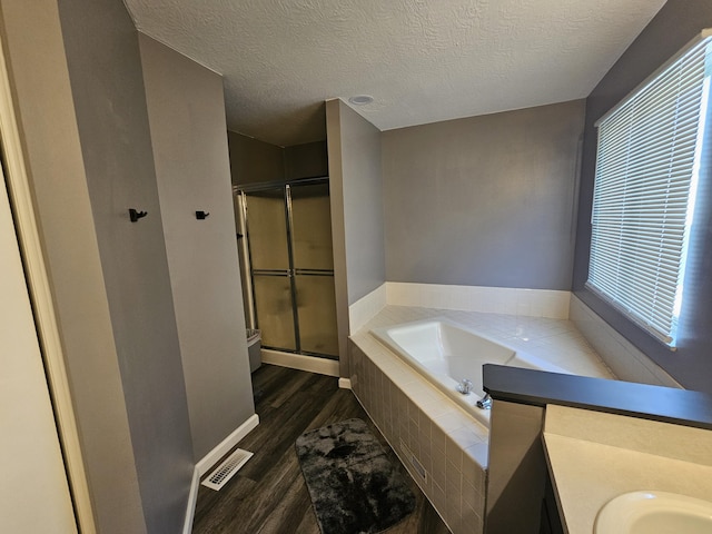 2973 Kicking Bird Trce, Dublin, OH 43017 - full bathroom featuring a garden tub, wood finished floors, a stall shower, a textured ceiling, and vanity