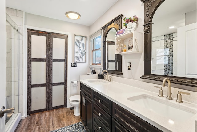 bathroom with wood finished floors, a stall shower, and a sink