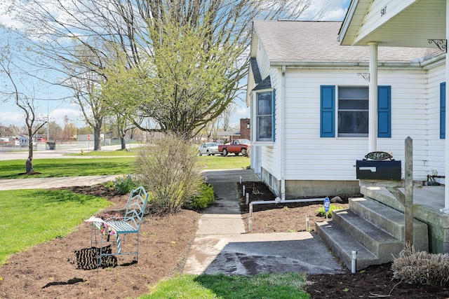 view of home's exterior with roof with shingles and a yard