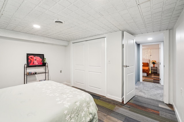 bedroom with recessed lighting, visible vents, dark carpet, and a closet