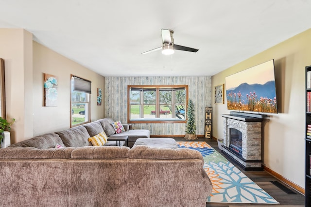 living area featuring an accent wall, wood finished floors, a fireplace, baseboards, and visible vents