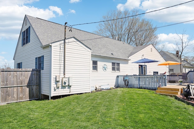 rear view of property featuring a yard, roof with shingles, fence, and a deck