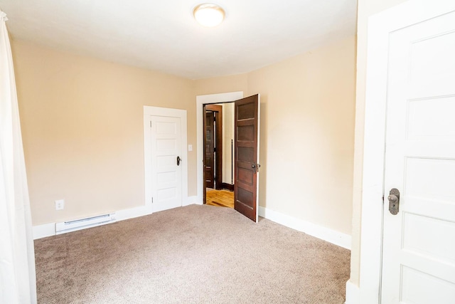 carpeted empty room featuring a baseboard heating unit and baseboards