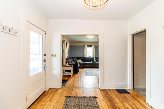 foyer entrance featuring ornamental molding, visible vents, baseboards, and light wood-style floors
