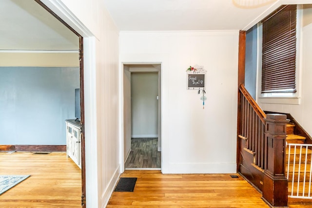 interior space with baseboards, visible vents, ornamental molding, and light wood-style flooring