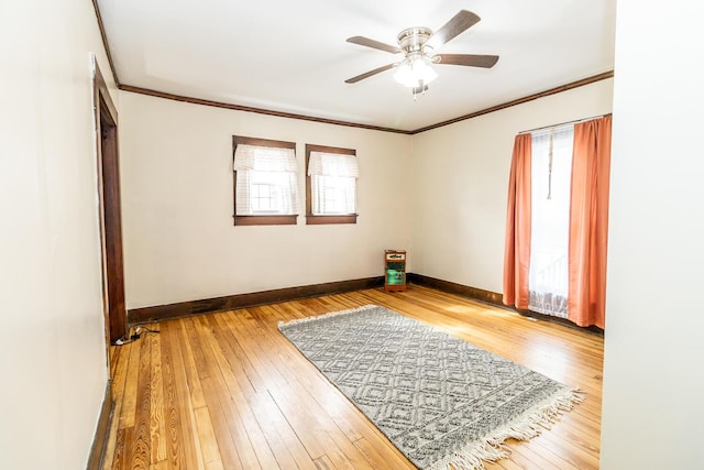 unfurnished room with hardwood / wood-style flooring, ceiling fan, crown molding, and baseboards